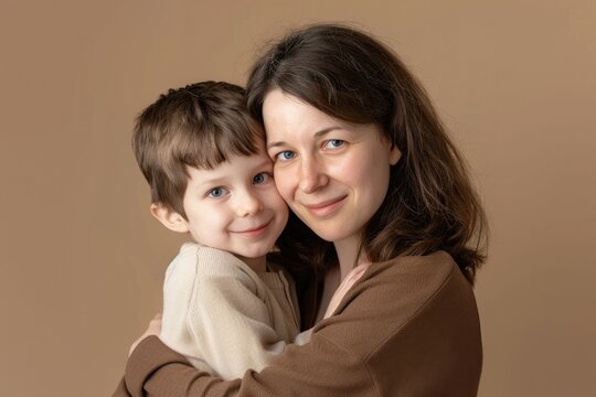 Mother hugging her son, Mother's Day concept, beige background.