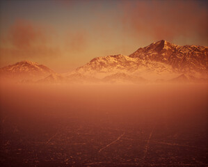 Frozen lake with snow mountains in mist under sunset sky with some clouds.