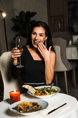 Luxurious woman in a black dress has dinner in a restaurant with flowers and a glass of champagne.Romantic dinner.International Women's Day concept