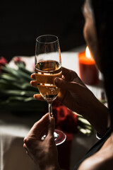Luxurious woman in a black dress has dinner in a restaurant with flowers and a glass of champagne.Romantic dinner.International Women's Day concept