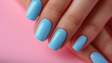 Female hand with blue manicure and nail polish on pink background.