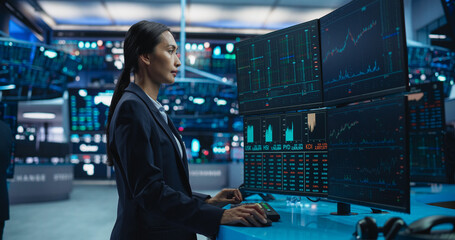 Young Female Stock Exchange Broker Working on Computer with Multi-Screen Workstation with Real-Time...