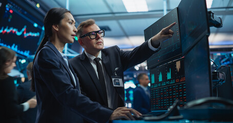 Team of Two Multiethnic Stock Exchange Brokers Using Computer, Chatting About the Asset Management...