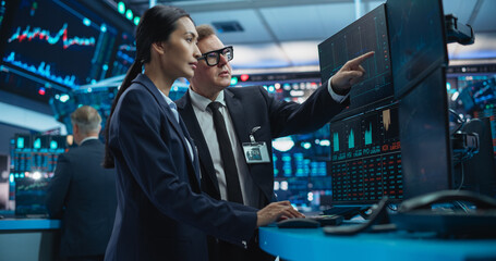 Financial Analysts Using a Computer with Multi-Monitor Workstation with Real-Time Graphs, Financial...