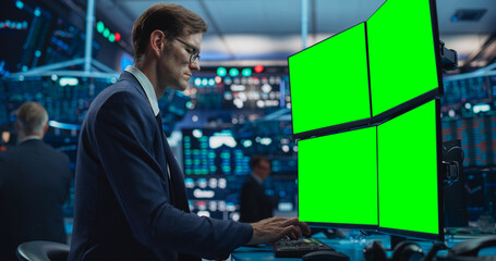 Portrait of Young Handsome Stock Exchange Broker Working on Computer With Green Screen Chromakey On...