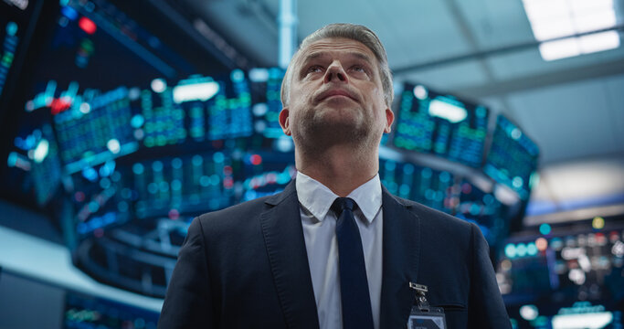 Portrait of a Handsome Adult Stock Exchange Broker Working in the Hall, Monitoring Real-Time Stocks Data, Analyzing Commodities and Exchange Market Charts. Professional Investment Agent in Office