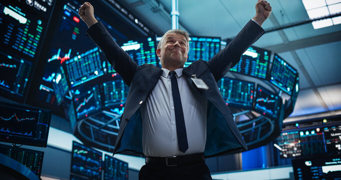 Stock Market Day Trader Working at an Exchange Office with Multi-Monitor Setup with Real-Time Investment, Commodities and Foreign Funds Charts. Happy Businessman Celebrating a Successful Trade