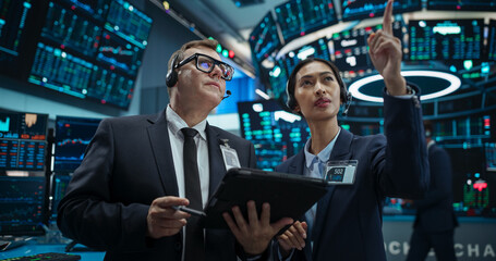 Team of Male and Female Stock Exchange Brokers Using Tablet Computer, Chatting About the Asset Management Strategy for an International Business Client, Working in a Office Building with Computers