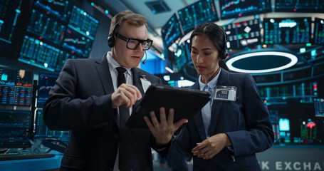 Team of Male and Female Stock Exchange Brokers Using Tablet Computer, Chatting About the Asset Management Strategy for an International Business Client, Working in an Office Building with Computers