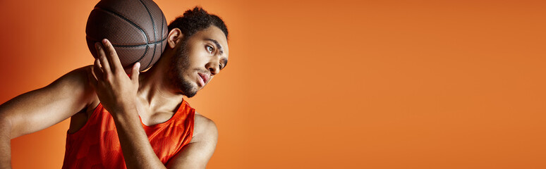 young african american man in sport clothes with basketball posing on orange backdrop, banner
