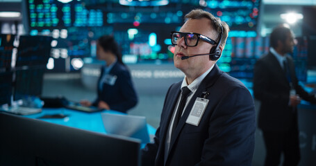 Portrait of Professional Middle Aged Trader Working on a Stock Exchange. Stylish Adult Man Communicating Buy and Sell Orders on a Call and Showing Hand Signals to an Arbitrage Broker