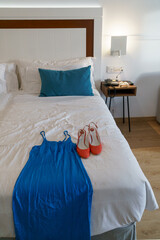 Vestido de fiesta azul y tacones rojos encima de la cama de un hotel de lujo 