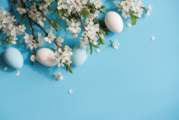 Blue and white eggs amidst cherry blossoms on blue background evoking Easter and spring