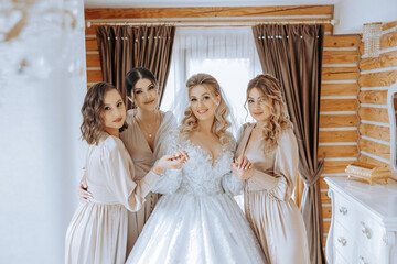 Bridesmaids rejoice in the morning, helping to fasten the buttons on the wedding dress and prepare...