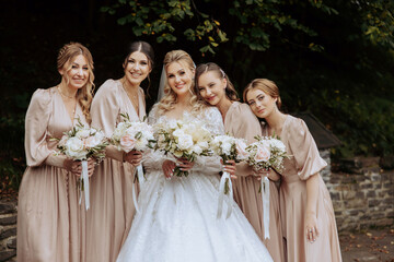 Wedding photography. A brunette bride in a white dress with a bouquet and her brunette girlfriends