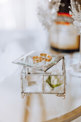 Wedding details. Gold wedding rings on a glass box with a silver frame