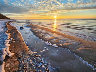 Sunset over the beach in winter. A beautiful landscape with a setting sun and a frozen sea, creating a mesmerizing view that captures the essence of the serene winter evening by the shore. - Powered by Adobe