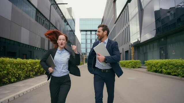 Corporate success company grows good result achievement end work day financial win victory triumph happy smiling excited two people business colleagues businessman businesswoman run in city celebrate