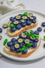 Fresh bread sandwiches with sweet blueberries, cream cheese and basil leaves. Good morning concept