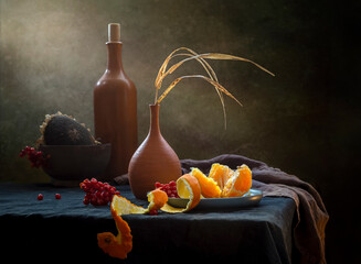 Modern still life with tangerine and dry grass in a clay vase on a dark background
