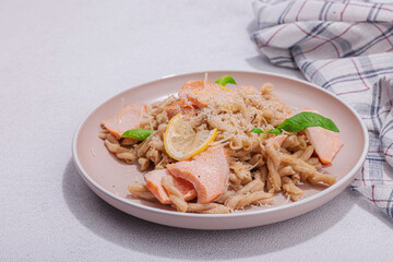 Plant based pasta with salmon, pesto and parmesan cheese. Ready to eat healthy food, served portion