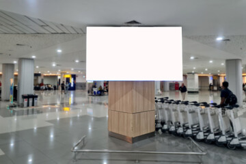 An empty billboard in a crowded airport with a trolley cart in the background. Public space blank...