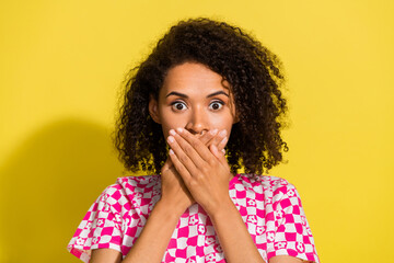Portrait of worried frightened girl arms palms covering mouth do not speak isolated on yellow color background