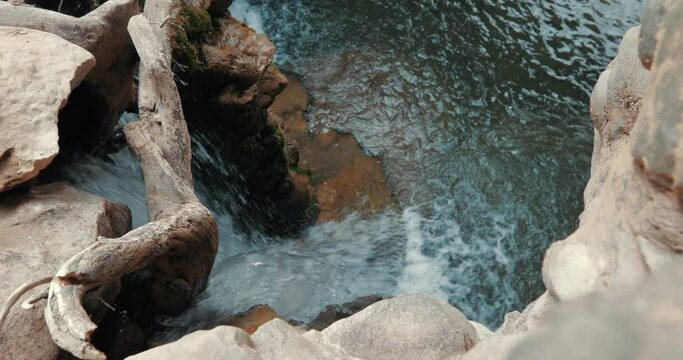 This is a close up view of the river. The eroded stream bed and a piece of wood can be seen.