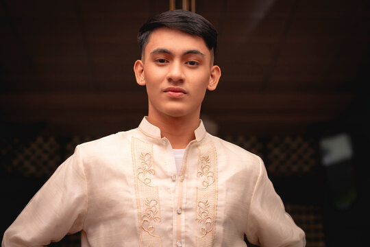 A young FIlipino man wearing a traditional Barong Tagalog shirt, inside an ancestral house.