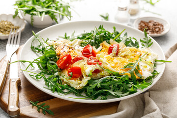 Fried eggs, omelette with onions, tomatoes and fresh arugula salad - obrazy, fototapety, plakaty