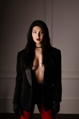 A sexy young Asian woman posing in a studio standing up. Fashionable filming of a swanky Asian brunette.