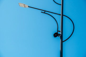 Lamppost with loudspeaker against blue sky.