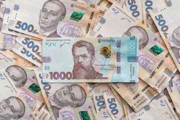 View from above on numerous 500 hryvnia banknotes on a flat surface, 1000 banknote in the center. Concept on richness, wealth, high earnings and investment in Ukraine