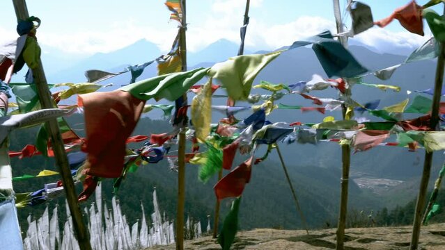 Panning view of the Himalayan mountains seen through a bunch of colourful fluttering prayer flags.