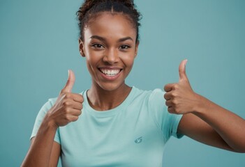 A woman in active wear with a bright, energetic double thumbs up. Studio shot with a blue background.