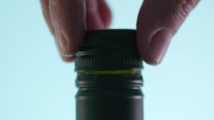 Fingers twist a cap onto a bottle. Close-up, shallow dof.