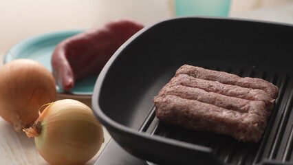 Place Cevapcici Sausages in Pan. Close-up, shallow dof.