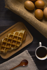 Waffles and coffee with boiled eggs on rustic wood background
