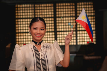 A proud young Filipina lady in a baro’t saya traditional dress, waving the Philippine Flag. Inside an ancestral house. - obrazy, fototapety, plakaty