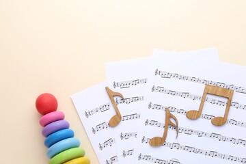 Wooden notes, music sheets and toys on beige background, flat lay with space for text. Baby song concept