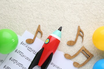 Wooden notes, music sheets and toys on beige textured background, flat lay with space for text....