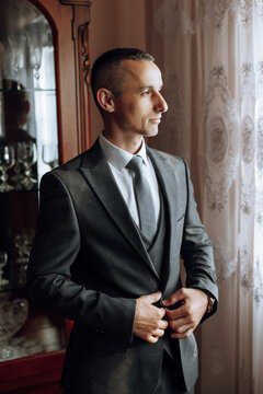 the groom's hands fasten his jacket in the morning before the wedding. close-up of a man in business suit. Businessman puts on a suit. The man fastens the buttons on his jacket.