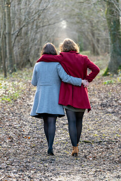 Couple de femmes photographi&eacute;es de dos marchant dans la for&ecirc;t