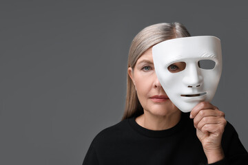 Multiple personality concept. Woman with mask on gray background, space for text