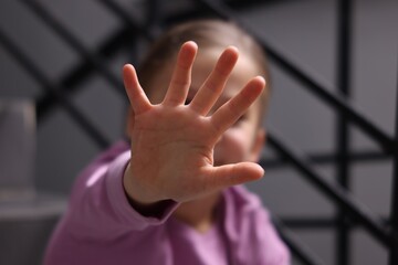Child abuse. Girl making stop gesture sitting on stairs, selective focus