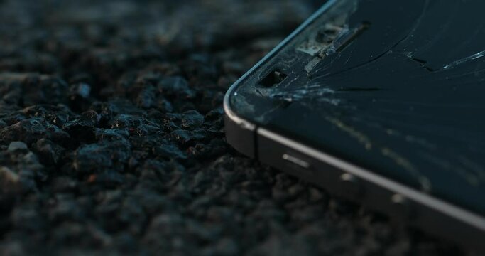 Broken Smartphone with a Cracked Screen on the Asphalt of the Road. Accident or Crime Scene. Close-up, Shallow DOF.