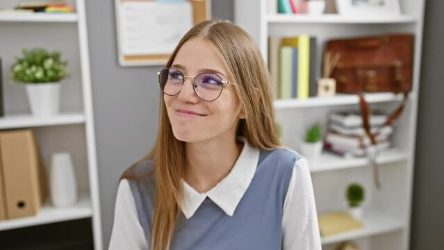 Smiling young businesswoman lost in thought, blondie side-glancing away with cheerful glow in office interior