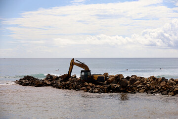 Fototapeta premium Trucks and excavators are working to unload material for a reclamation project on the coast of Bali, Indonesia. the process of making embankments on the beach to anticipate abrasion.