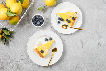 Traditional French lemon pie with blueberries on a white stone background.