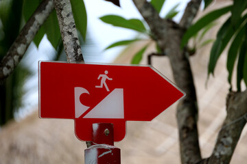 Tsunami warning board on the beach, outdoor tsunami sign with directional arrows and evacuation...